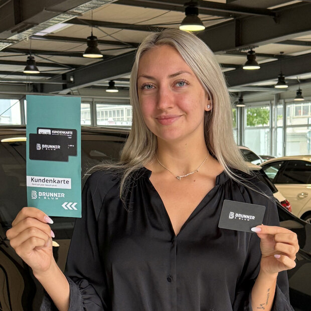 Brunner & Blum Kundenkarte Junge Frau präsentiert die Brunner & Blum Kundenkarte und den zugehörigen Flyer